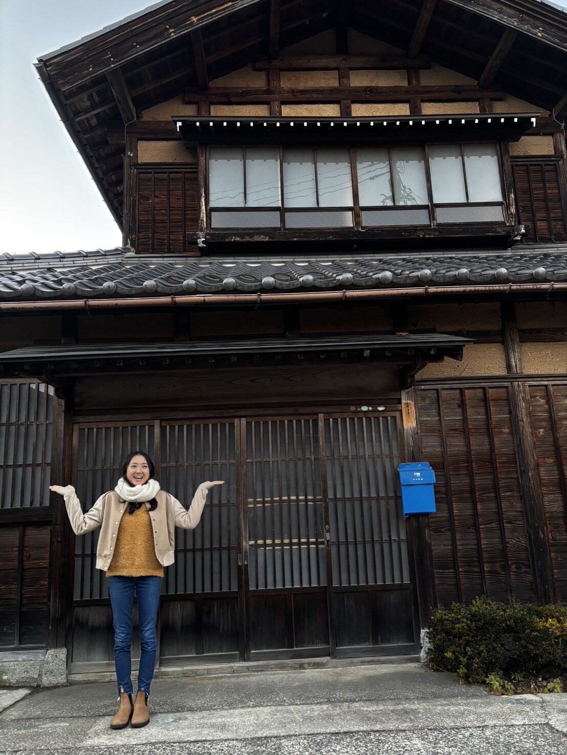 古民家の前に立つ笑顔の女性